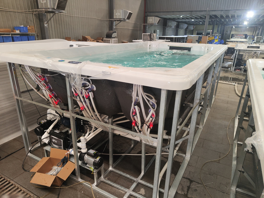 Valora swim spa operating with water while its plumbing and equipment area remain open for factory checks